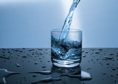 Glass of water on a table used as a visual for daily fluid intake awareness education